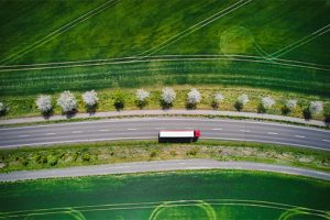 Drone shot direct above a truck moves along a single road.